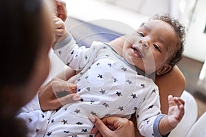 Happy three month old baby boy lying on his back on his motherÃ¯Â¿Â½s knee looking up at her, over shoulder view, close up